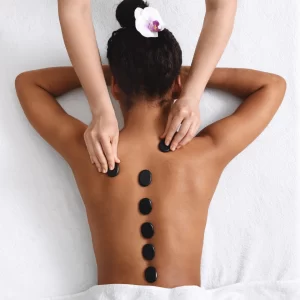 Mulher recebendo massagem com pedras quentes nas costas em clínica de estética em Indaiatuba-SP